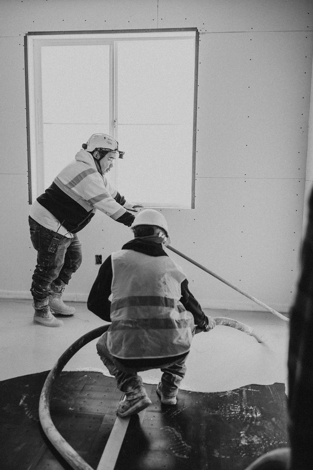 Two crew members screeding and guiding the hose, black and white
