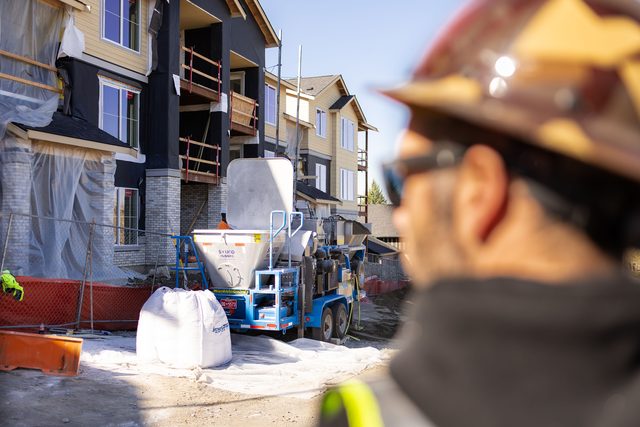Crew member overlooking the rig and materials in front of a multifamily building